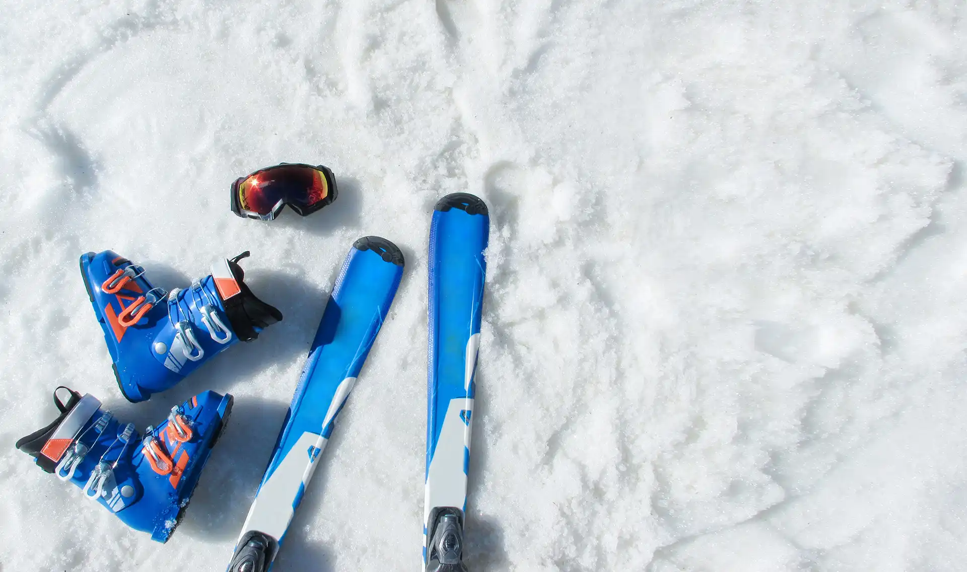Scarponi da sci blu, sci e maschera da sci su neve bianca.
