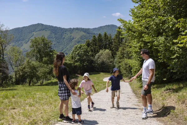 Famiglia che cammina lungo un sentiero di montagna in una giornata soleggiata.