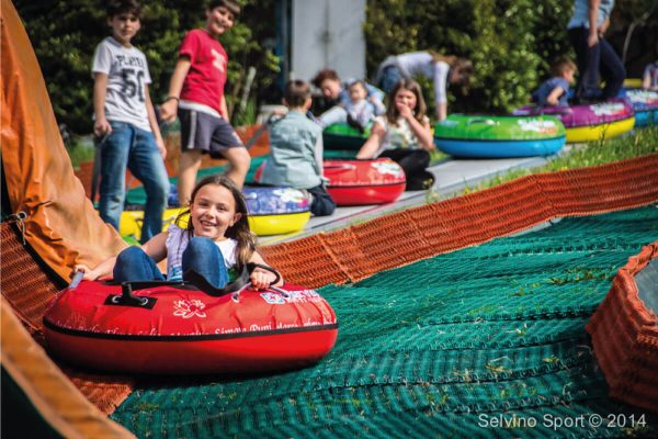 Bambini che si divertono su gommoni colorati in un parco giochi all'aperto.